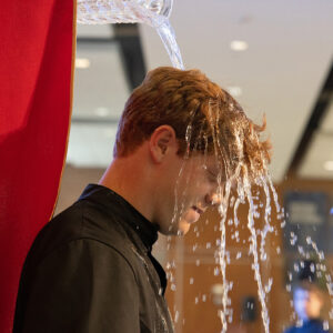 St. Louis University High School student Connor McCoy was baptized by Father Matt Stewart, SJ, principal of SLUH, during a school Mass on April 25.